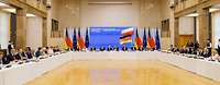 Regierungsvertreter Deutschlands und Polens sitzen an einem großen U-Förmigen Tisch, im Hintergrund Flaggen der EU, DE und POL. 