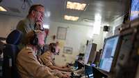 Boris Pistorius steht hinter einem Soldaten, der an einem Computer unter Deck einer Fregatte sitzt