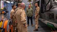 Boris Pistorius steht gemeinsam mit Soldaten neben einem Hubschrauber unter Deck einer Fregatte 