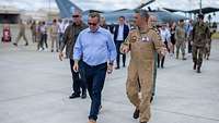 Boris Pistorius läuft gemeinsam mit einem Soldaten auf einem Flugplatz entlang