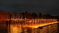 Bei Dunkelheit und Regen laufen Soldaten mit Fackeln in Formation.