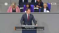 Staatssekretär Hitschler spricht im Bundestag an einem Rednerpult.