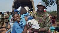 Ein UN Soldat hält lächelnd ein einheimisches Baby in Ghana. 