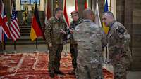 Der Generalinspekteur und weitere ranghohe Soldaten unterhalten sich im BMVg, im Hintergrund Flaggen