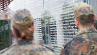 Soldaten stehen vor einer Tafel, auf der ein Auszug aus dem Grundgesetz steht.