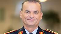 General Christian Badia schaut für eine Portraitaufnahme lächelnd in die Kamera.