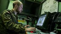 Eine Soldat sitzt an einem Computer