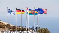 Die Flaggen von Griechenland, Deutschland, Frankreich, NAMFI, Amerika und der NATO wehen am Fahnenmast
