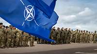 Internationale Soldaten und die NATO-Flagge