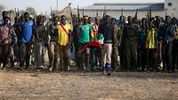 Afrikanische Männer mit Speeren in den Händen stehen nebeneinander.